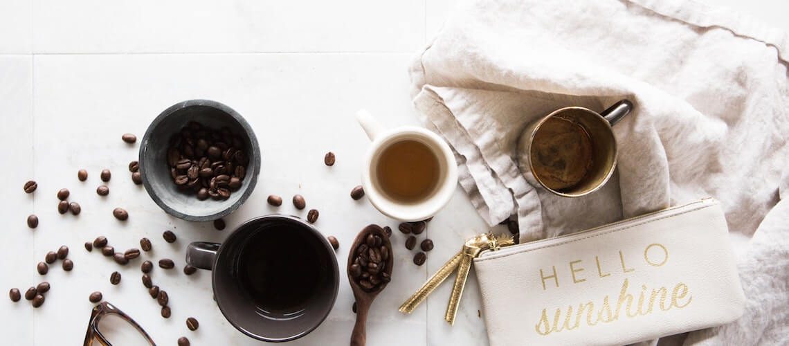 A flatlay of a cup of tea and some bowls on a white table top